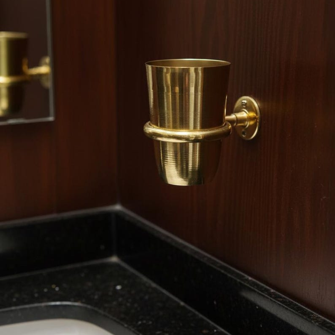 Brass cup holding essentials on a tiled bathroom wall
