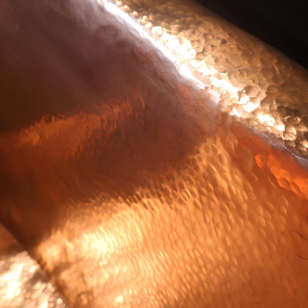 Warm light on hammered copper surface — texture glow and depth