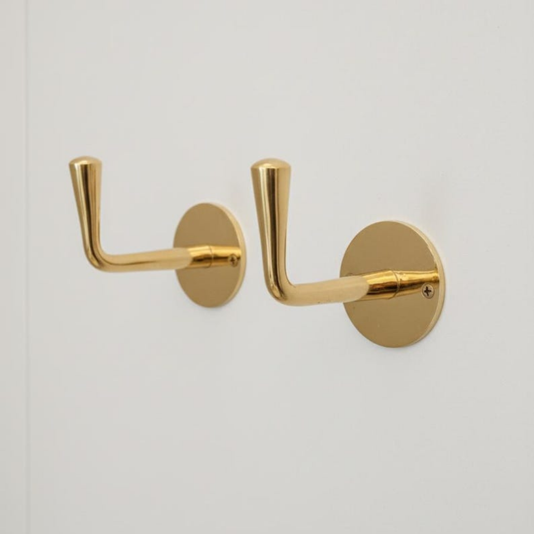 Brass hooks arranged in a minimalist bathroom